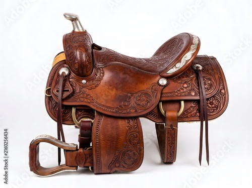 Hand tooled western leather saddle with silver accents sits on a white background