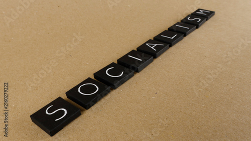 Foto Word socialism spelled out using black square letter tiles, representing the pol