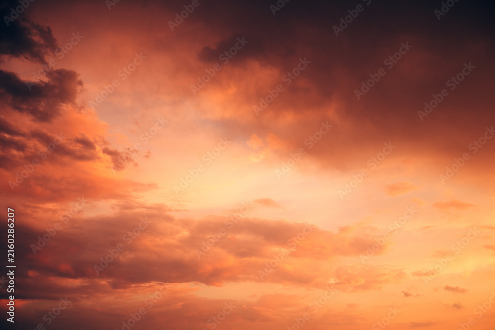 Fototapeta premium Spectacular fiery orange sky filled with towering storm clouds and dark atmospheric formations. Dramatic sunset, approaching storm, extreme weather concept.