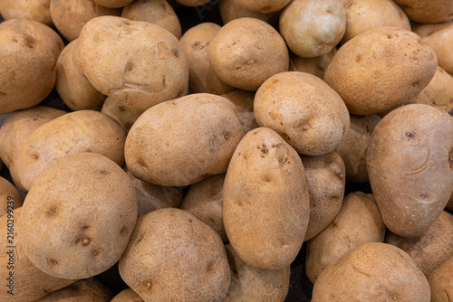 Abundant pile of fresh, earthy potatoes with golden brown skin and subtle light showcasing natural textures and healthy organic produce