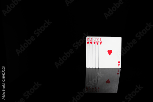 Quadro su tela Royal flush of hearts playing cards on black background with mirror reflection