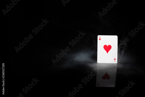 Quadro su tela Ace of hearts playing card in dramatic smoke on black background with reflection