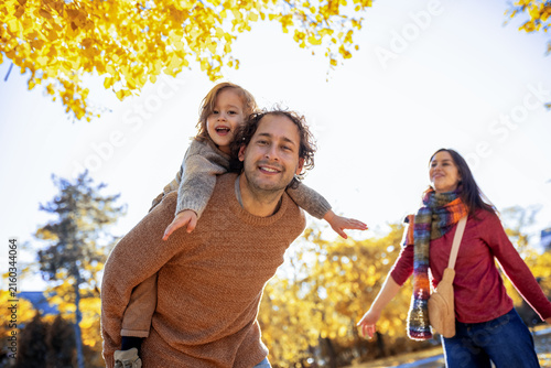 Foto Family walking and playing with piggyback ride in fall