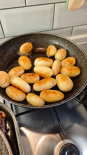 Cuadro en lienzo Golden-brown baby potatoes frying in a non-stick skillet on a stovetop with a mo