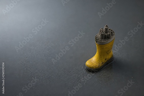 Rain boot with sandcastle top on dark textured background