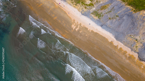 Aerial view of the sandy beach and dramatic cliffs along the Jurassic Coast in Lyme Regis, England, United Kingdom.