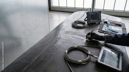 Professional Technician Performing Ultrasonic Nondestructive Testing on Metal Aircraft Fuselage Surface in Industrial Hangar