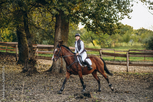 Quadro su tela A young beautiful woman jockey is preparing for a show jumping competition