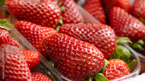Strawberries in a plastic container, at a street market, in a supermarket.