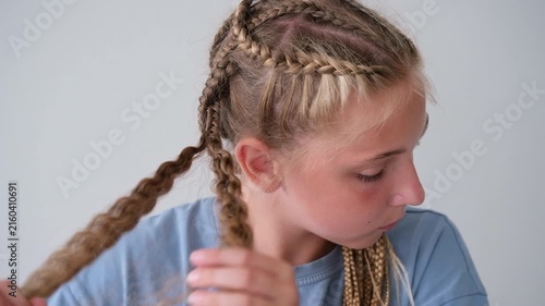 The girl is unbraiding her braids. Her hair has become curly.