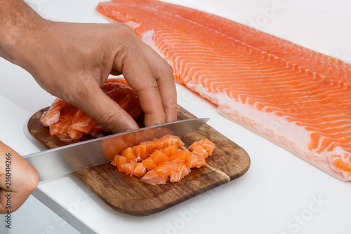 Dicing Fresh Raw Salmon Fillet into Cubes on Wooden Cutting Board