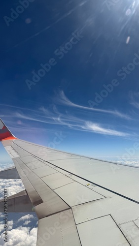 Konstfotografi Vista da asa de avião durante voo acima das nuvens sob céu azul 2026