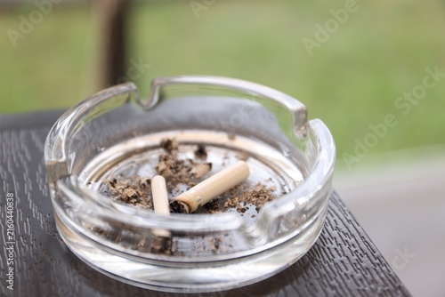 Fotografía Cigarette butts in ashtray on wooden table outdoors, closeup