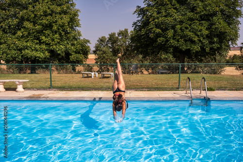Woman dive headfirst into outdoor swimming pool