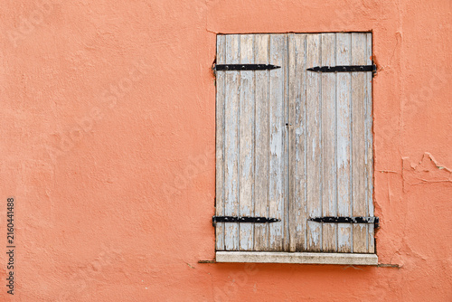 Vintage wooden window on a weathered plaster wall of an historic house
