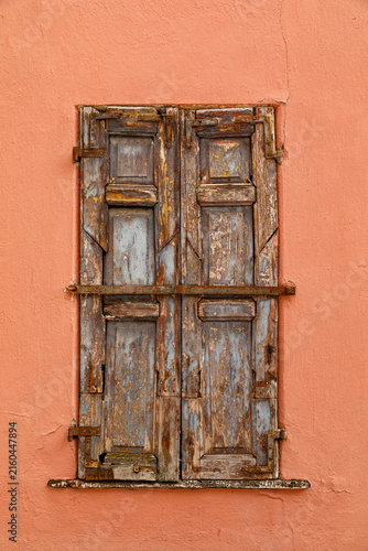 Vintage wooden window on a weathered plaster wall of an historic house
