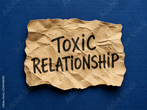 Toxic relationship text on crumpled paper. Emotional abuse concept on torn craft note.