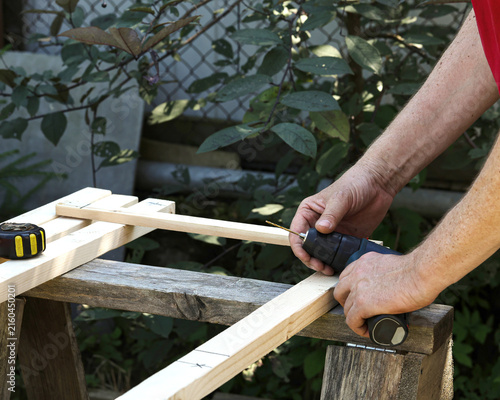 Woodworker drill timber frame during outdoor carpentry work