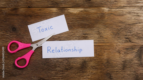 Scissors cutting paper with toxic relationship text. Ending a bad connection concept.