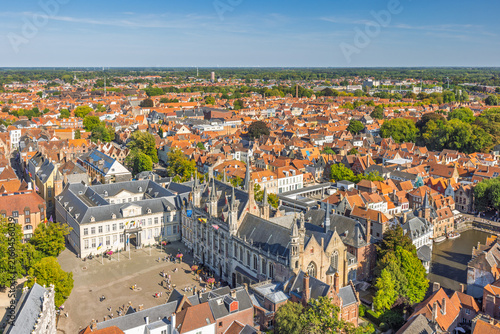 Bruges town in Belgium, Europe. Aerial panorama of a historic European city, featuring charming architecture, a bustling market square, and a picturesque canal under clear blue sky