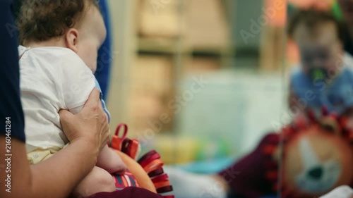 Parent supporting a baby looking at its reflection in a mirror, fostering early childhood exploration and self-discovery in a playroom