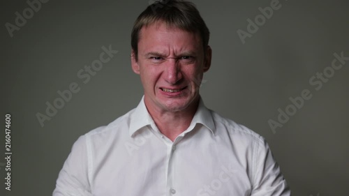 Businessman in a suit looking at the camera with a angry and disappointed facial expression. Studio portrait isolated on a white background, suitable for business, stress andal concepts.