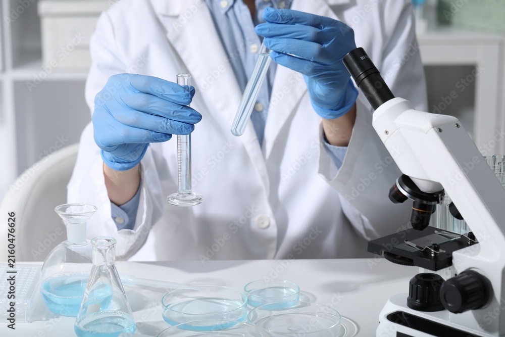 Fototapeta premium Scientist with test tubes in laboratory, closeup