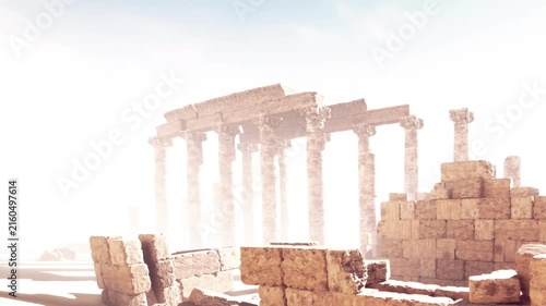 Stone columns and walls are visible in the desert under bright sunlight. Sand surrounds the aged structures, showing signs of weathering and time.