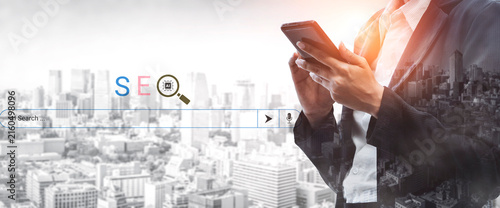 Bild auf Leinwand Business professional holds smartphone in urban setting, symbolizing engagement in digital marketing and search engine optimization for modern business strategies