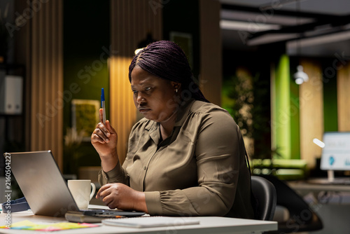 Quadro su tela Executive manager envisions a tactical solution while playing with a pen at her desk after hours, using critical thinking to evaluate options from different perspectives and make business decisions