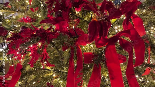 Christmas tree decorated with red ribbons and warm lights, festive close up