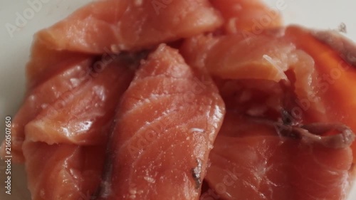 Fresh raw salmon fillets, sliced and lightly seasoned with salt, rest inside a clear glass dish in a close-up macro shot. For culinary commercials, seafood recipe tutorials, healthy eating promotions.