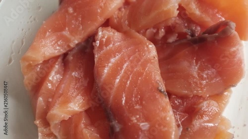 Fresh raw salmon fillets, sliced and lightly seasoned with salt, rest inside a clear glass dish in a close-up macro shot. For culinary commercials, seafood recipe tutorials, healthy eating promotions.