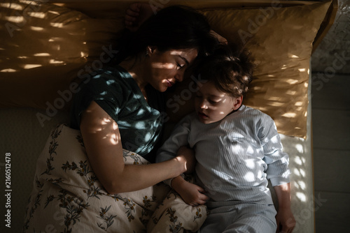 Cuadro en lienzo Mother and son sleeping together in dappled morning light