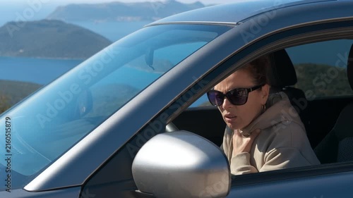 Woman with asthma attack using an inhaler while driving a car. Female driver having an asthma attack and using an inhaler to relieve her symptoms, sitting in her car by the sea