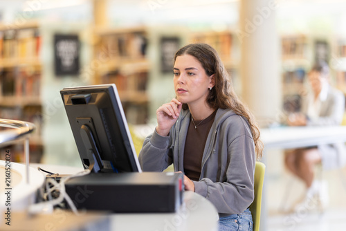 фотографія Young woman student working or studying at computer in library