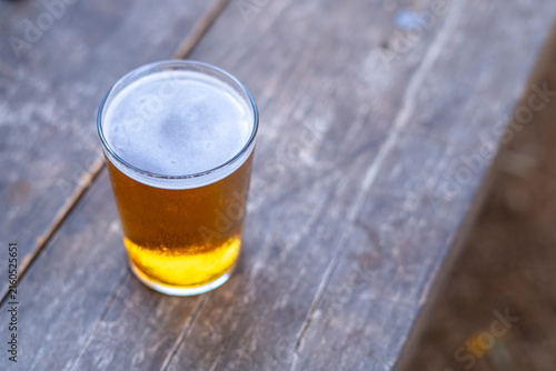 Full Glass of Beer on a Rustic Wooden Table. Cold Beer in a Glass on a Wooden Table. Full Beer Glass with Foamy Head on Rustic Wood.