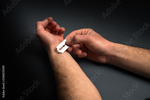 Fotografía Distressed individual holding a razor against the wrist, depicting a suicide attempt and severe emotional crisis, highlighting the importance of mental health awareness, intervention, and support