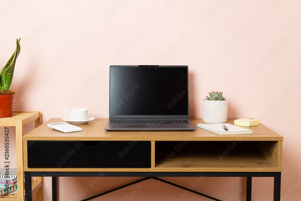 Fototapeta premium Comfortable workspace with laptop, notebook and flower