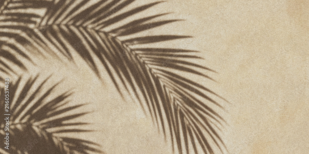Fototapeta premium Palm leaf shadow on textured beige sand background for summer travel and vacation concept