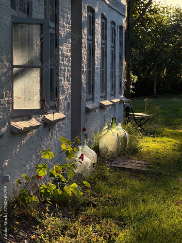 Glass demijohns standing by cottage wall in rural Germany