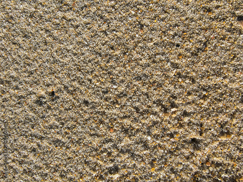 This detailed macro shot of wet golden sand on a serene beach evokes the peaceful warmth of summer days and tranquil ocean shores. Perfect as a natural texture background. Nobody.