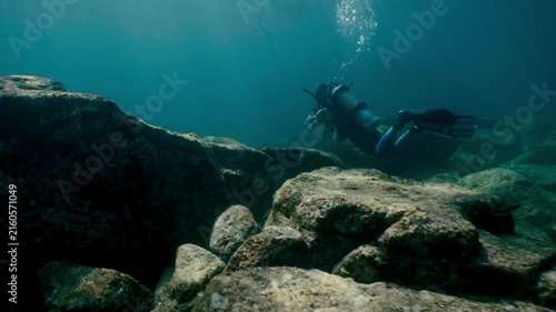 Scuba diver exploring rocky underwater seabed