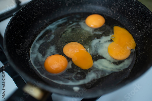 Raw eggs frying on black skillet 