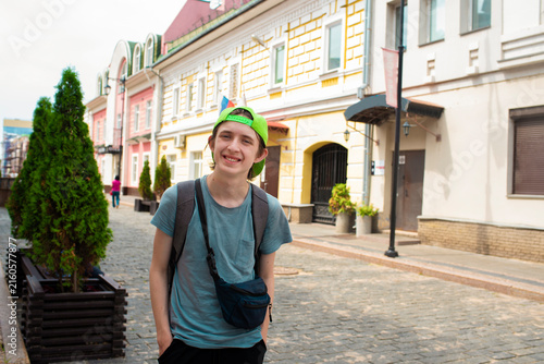 Happy teenage boy tourist walking on city street during summer travel