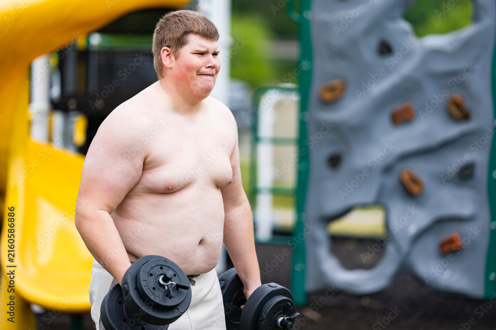 Naklejka premium Workout begins on playground. Overweight workout shows effort. Outdoor workout with dumbbells. Workout supports healthy lifestyle.
