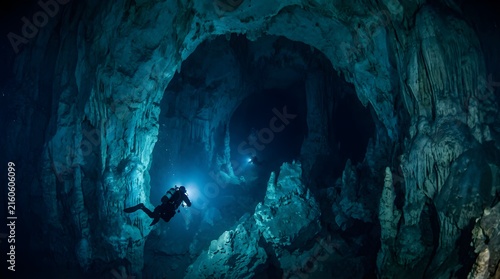Obraz na płótnie Scuba divers exploring a dark underwater limestone cave with flashlights