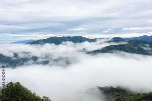 Bild auf Leinwand Misty mountain ridge above cloud layer beneath overcast sky, creating tranquil n