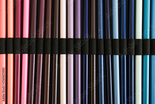 close-up of pink purple and blue colored pencils neatly lined up in pencil case, concept of creativity, drawing, education and art supplies