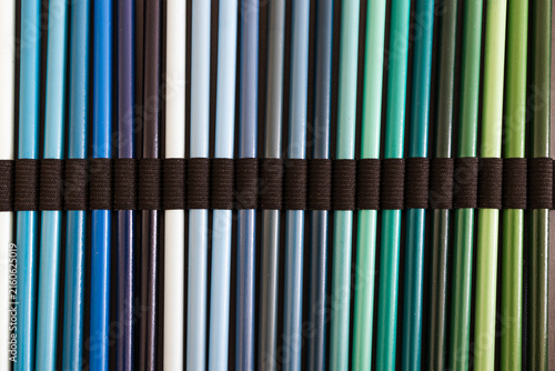 close-up of blue turquoise and green colored pencils neatly lined up in pencil case, concept of creativity, drawing, education and art supplies